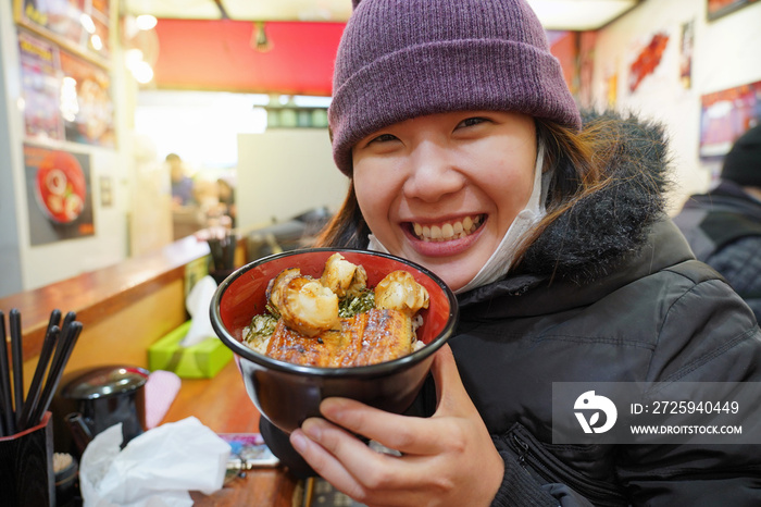  Asian young woman enjoy with japanese food which have rice with eel griled and scallop in the bowl 