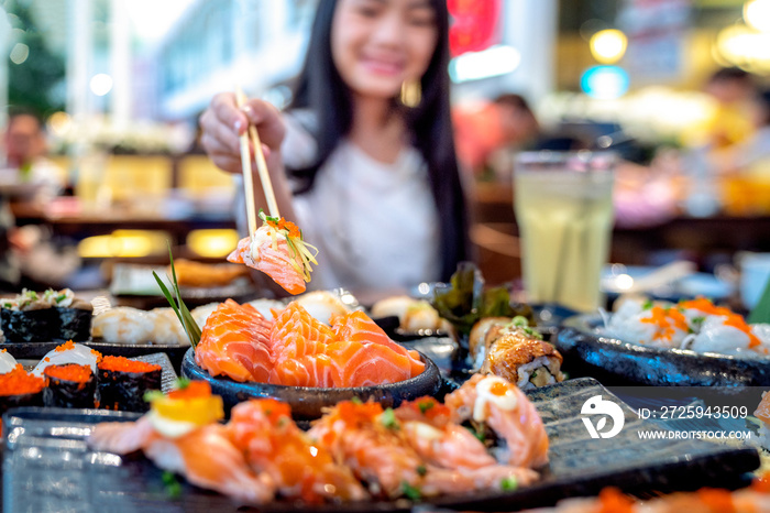 Asian lady eat a Salmon fish sashimi and Sushi in Japanese restaurant