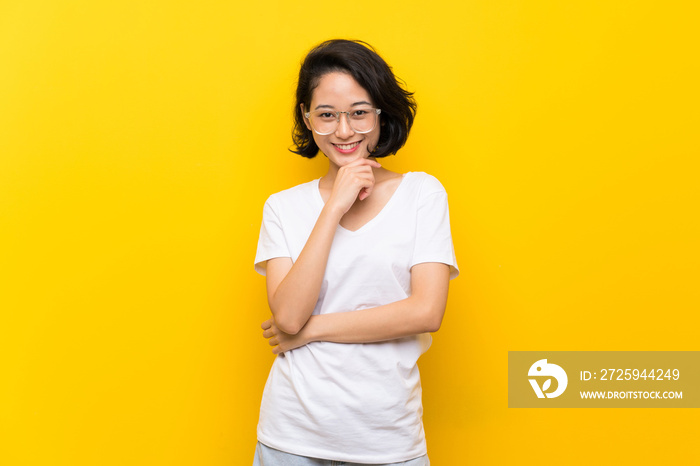 亚洲年轻女子戴着眼镜微笑着越过隔离的黄色墙壁
