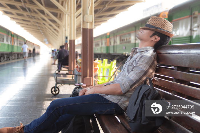 Asian man wearing a hat weave lying on a bench wooden. Waiting for the train at station in the outbo