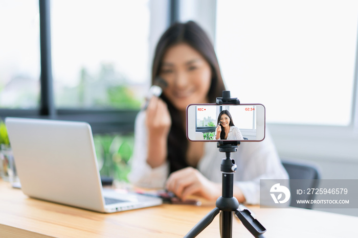 Young Asian cute artist woman beauty vlogger or blogger doing a cosmetic makeup tutorial vlog with b