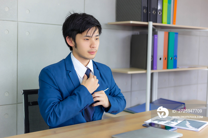 Handsome young businessman ties necktie at office. It’s the first day for working. Attractive handso