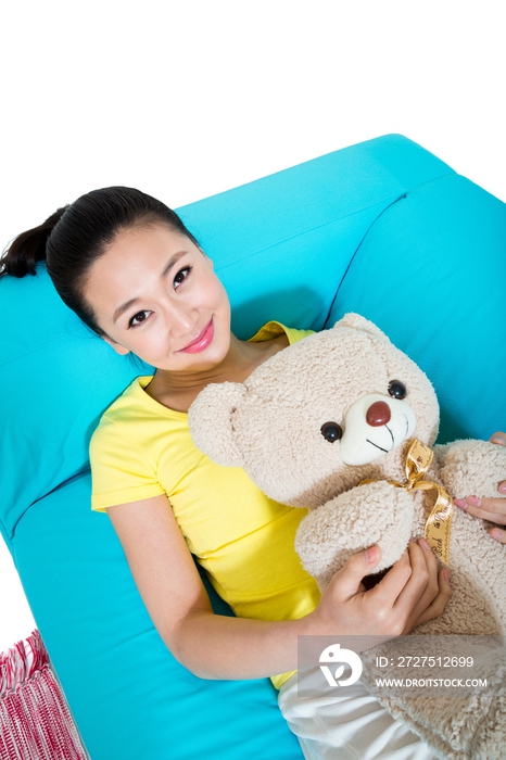 棚拍年轻女人坐在沙发上玩玩具熊