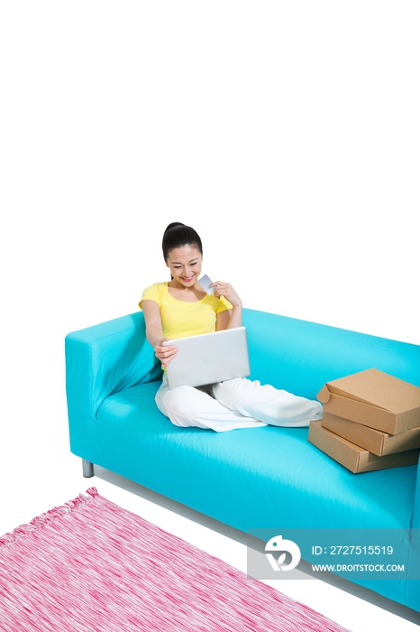 棚拍年轻女人坐在沙发上上网购物