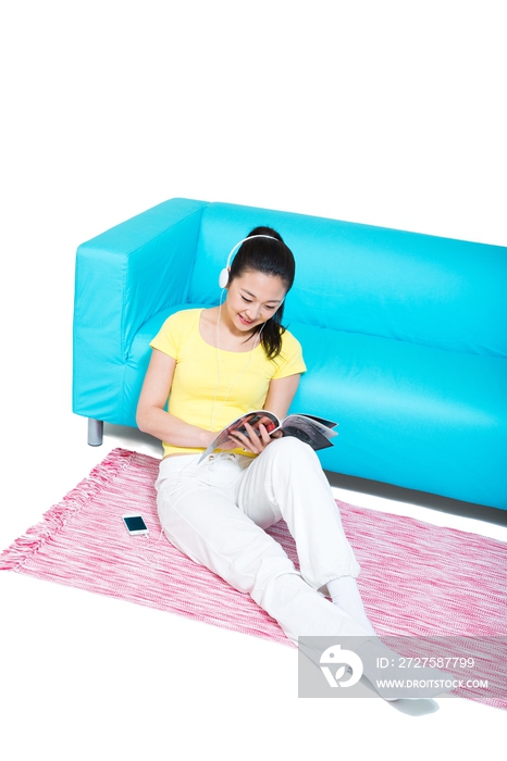 棚拍年轻女人坐在地毯上听音乐看杂志