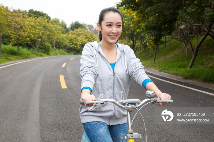 一个年轻女大学生在校园里骑车