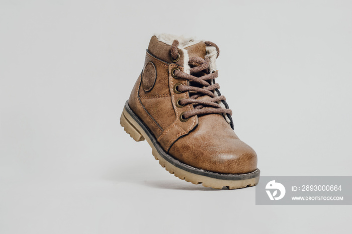 Leather, childrens shoe on a light gray background. A childs shoe made of brown leather with insul