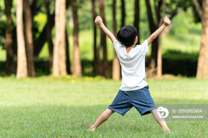 Rear view asian boy raising arms in the public park. The child was raising both arms in joy. Life ac