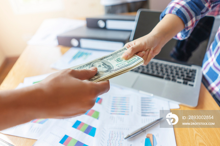 close up of businessman receiving money bills, representing getting paid monthly salary, across the 