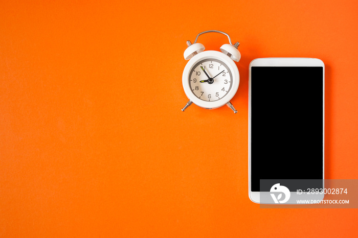 white alarm clock and mobile phone with clipping part on touch screen on grunge orange background fo