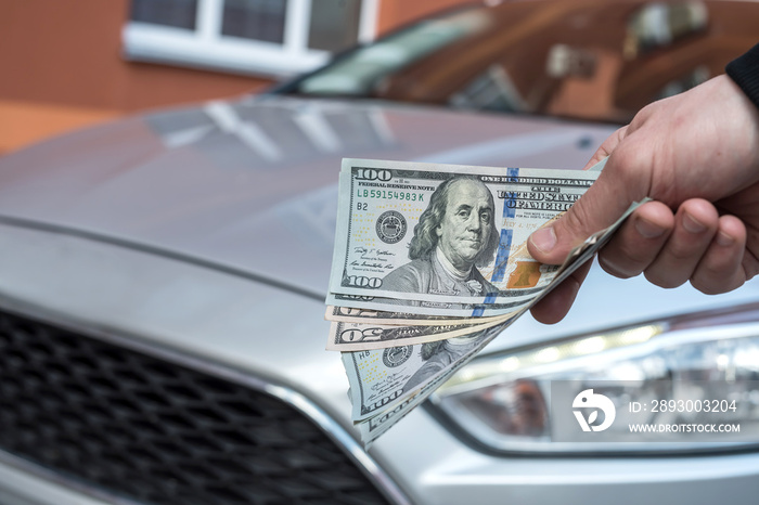 male hand dollar, take money on car background