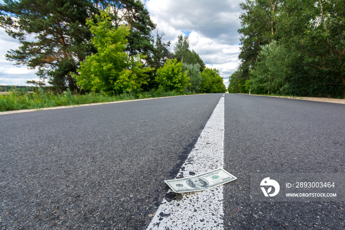 Dollar bills on asphalt road