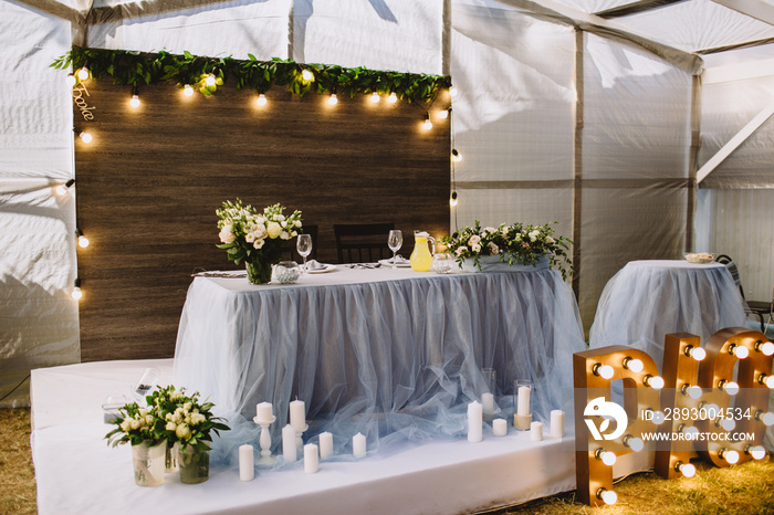 Festive table decorated with composition of flowers and greenery, candles in the wedding banquet hal