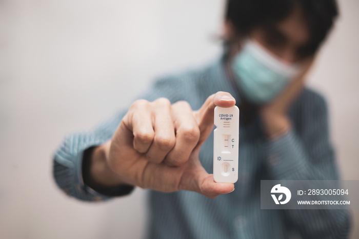 A man holds the rapid antigen test kit with positive result during the COVID-19 test of the sample.