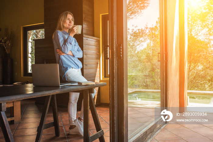 Working from home. Woman with laptop and drinking tea, spend free time on terrace. Staying connected