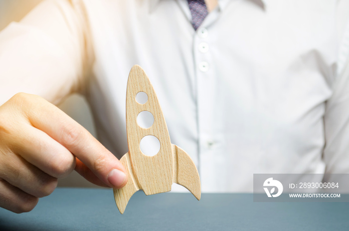 Businessman holds a wooden rocket in his hand. The concept of raising funds for a startup. Charitabl