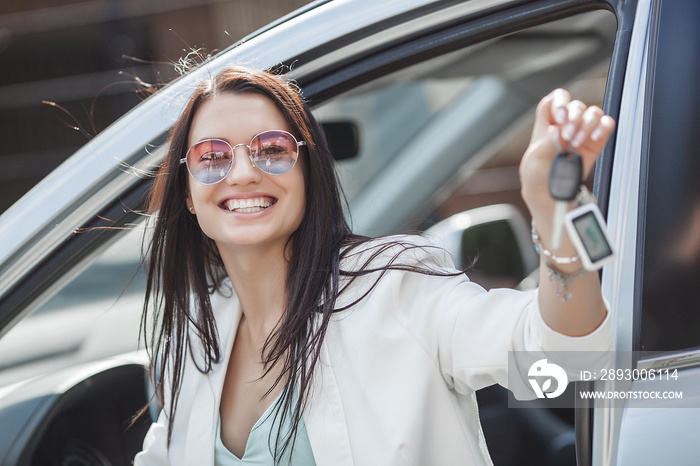 Young attractive woman just bought a new car. female holding keys from new automobile.