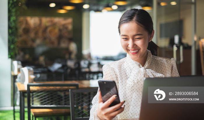 Asian woman using mobile phone and laptop computer for working business and technology concept