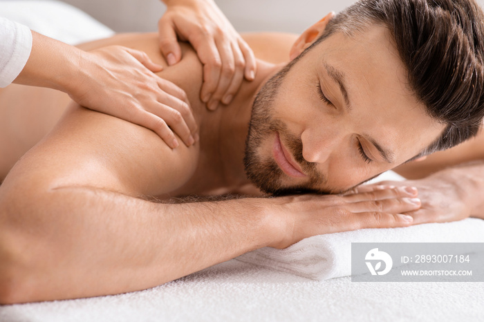 Closeup of relaxed man having body massage at spa