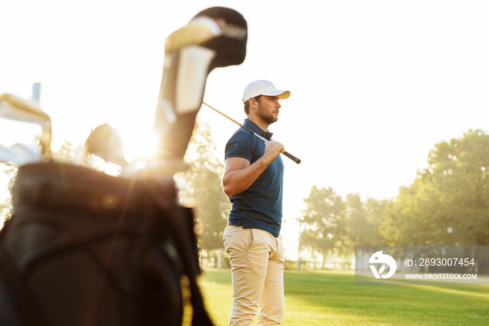 Male golfer holding driver while standing