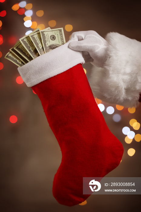 圣诞老人拿着装有钞票的袜子对着散焦的灯光