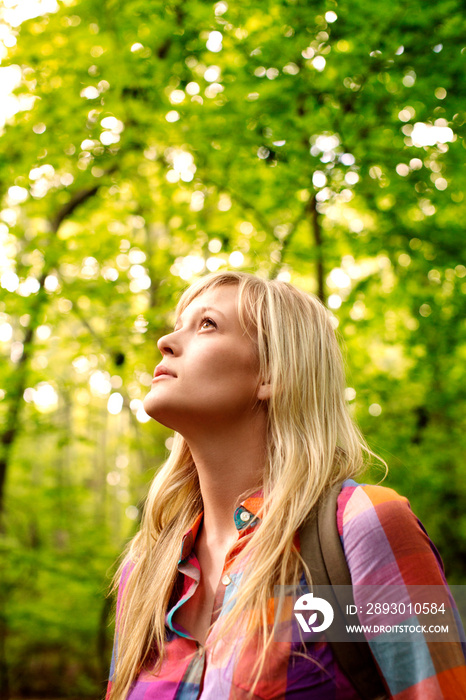 Young woman looking up in forest