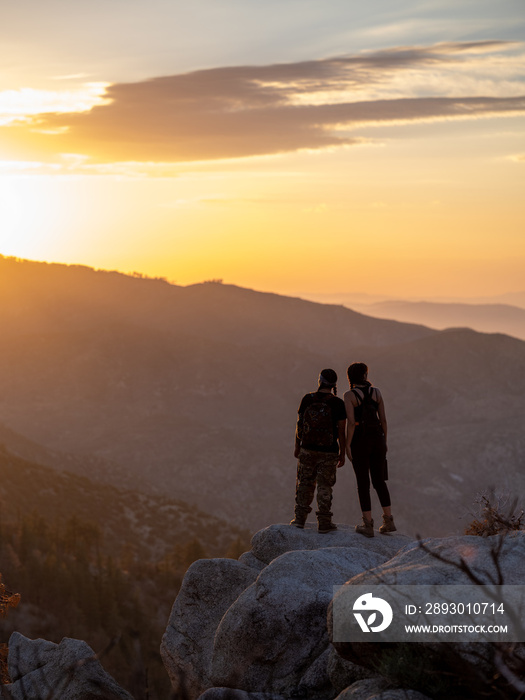 年轻的本地朋友站在悬崖边观看日落的垂直图像