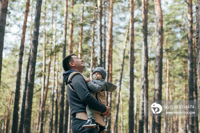 Dad carrying his 1 years old son in ergo carrier. Authentic moment. Concept of leisure outdoor