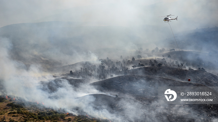在森林火灾或野火中使用水桶滴水的消防直升机。
