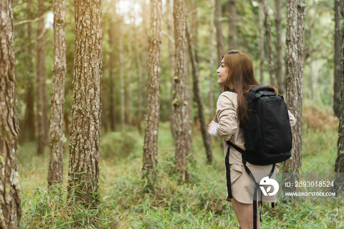 快乐的女人背着背包在森林里旅行和行走