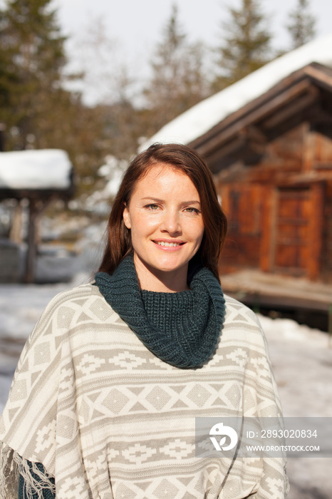 阳光明媚的雪地小屋外微笑的女人画像