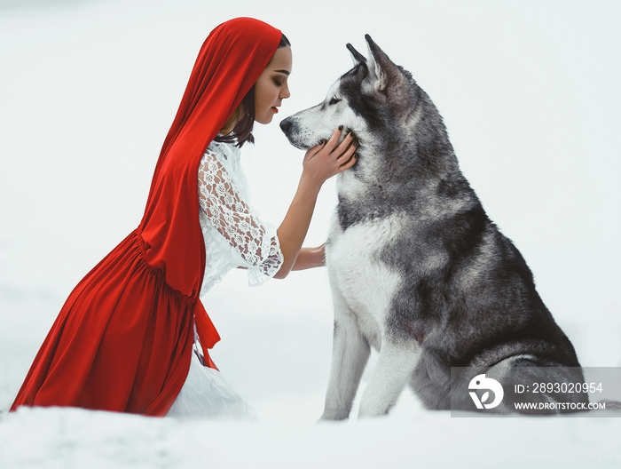 Girl in costume Little Red Riding Hood with dog malamute like a