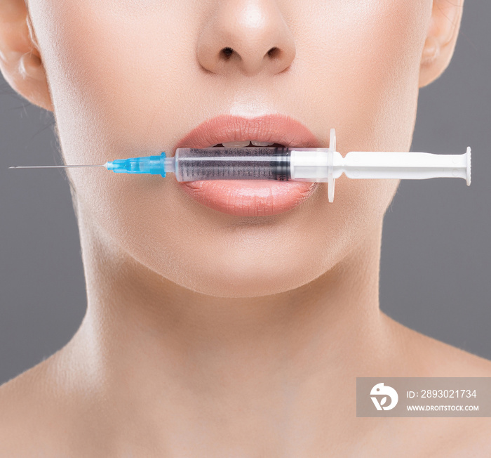 Young woman with syringe in her mouth close up