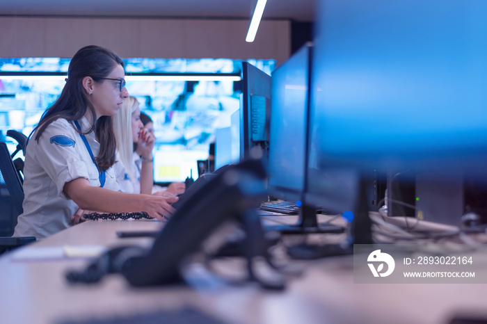 Group of security guards working on computers while sitting in the main control room, CCTV surveilla