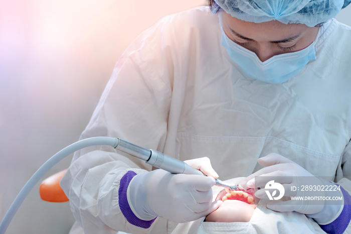 Female Asian dentist using instruments for curing and drilling patient teeth in dental clinic. Denta