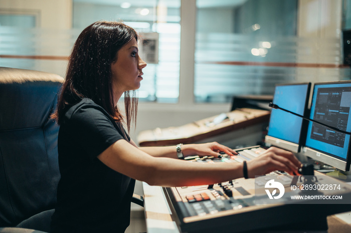 Young beautiful woman working in a broadcast control room on a tv station