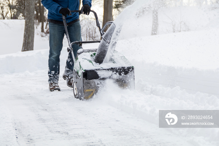 Snow blower in action clearing a residential driveway after snow storm