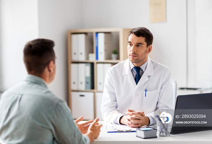 medicine, healthcare and people concept - doctor talking to male patient at medical office in hospit