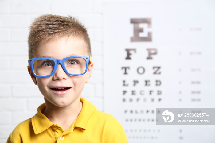 Little boy with spectacles on ophthalmic test chart background