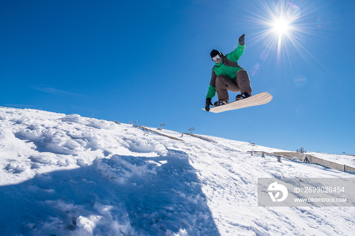 Snowboarder jumping against blue sky