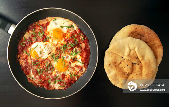 Shakshuka-铁锅里的番茄酱荷包蛋、洋葱、胡椒和香料配皮塔面包