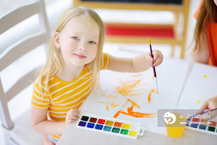 Cute little girl drawing with colorful paints at a daycare