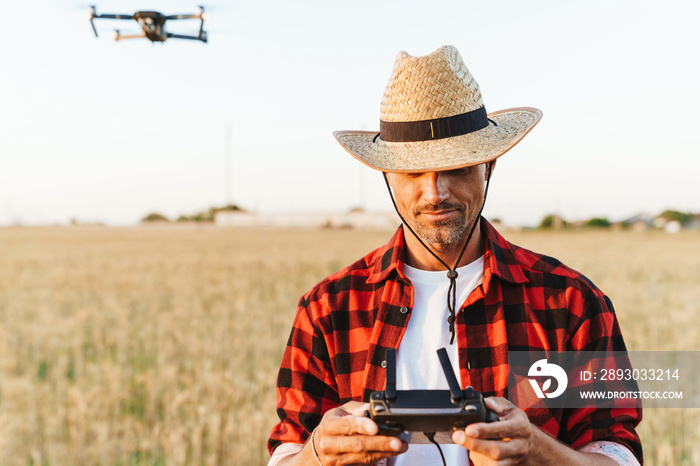 快乐的英俊男子站在麦田里使用无人机的画面