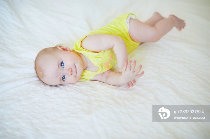 Adorable baby girl lying on bed