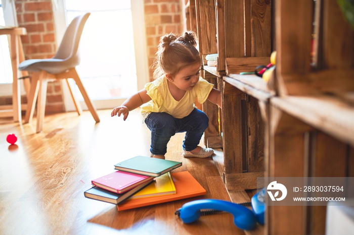 Beautiful toddler taking books of shelving at kindergarten