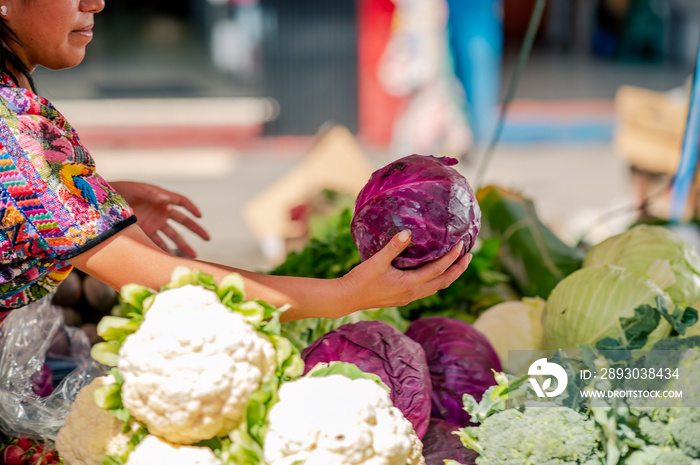 Mujer indigena sostiene en sus manos vegetales frescos en un mercado local de Guatemala.