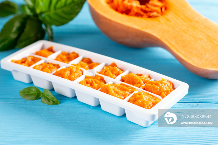 Ice cube tray with healthy baby food on blue table