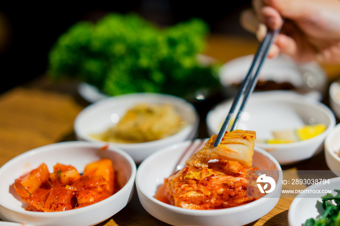 在餐厅里，女人用手拿着筷子吃泡菜沙拉。韩国食物传统泡菜