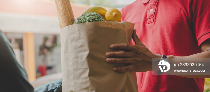 Web banner. smart food delivery service man in red uniform handing fresh food to recipient and young