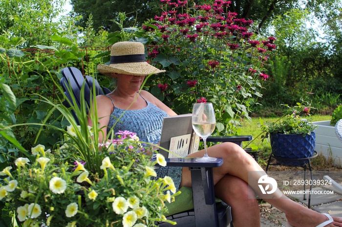 Relaxed and Happy Mature Adult Woman 50-59 enjoying a glass of wine in her garden glass